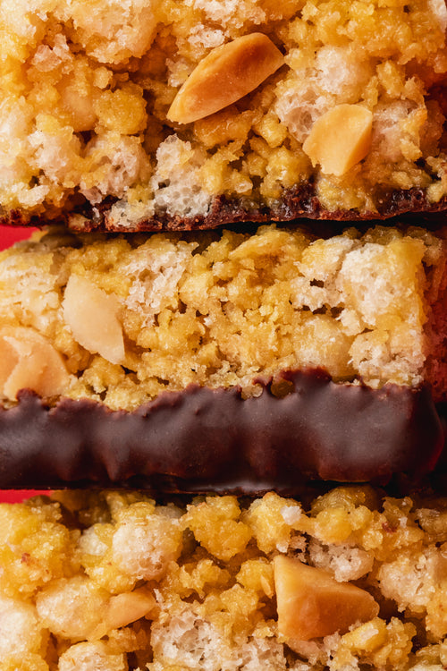 Barre protéinée chocolat et cacahuète Funkie emballée entourée d'arachides et de chocolat noir sur fond rouge