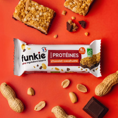 Barre protéinée chocolat et cacahuète Funkie emballée entourée d'arachides et de chocolat noir sur fond rouge